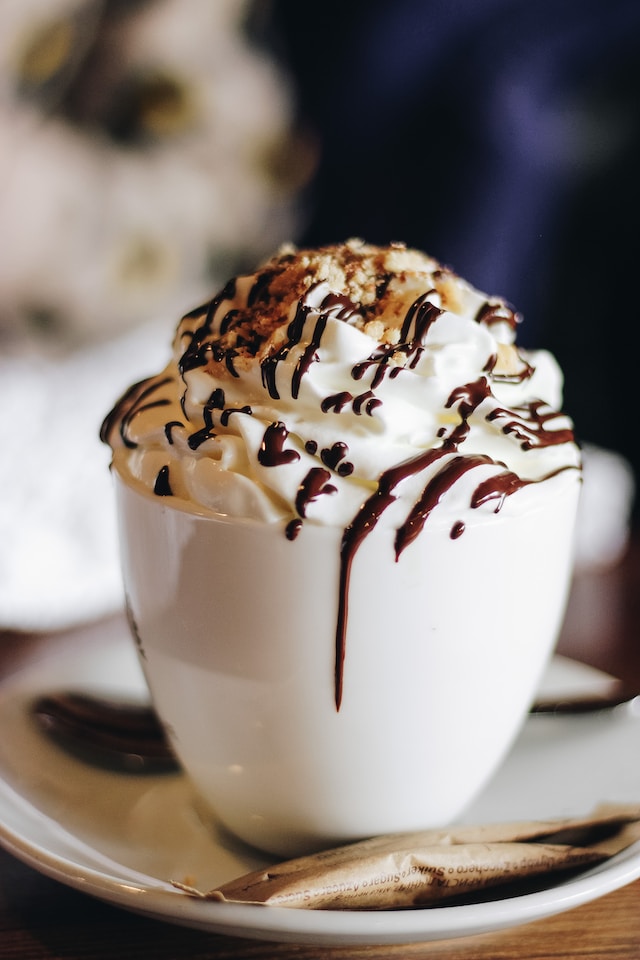A cup of hot chocolate with whipped cream and chocolate