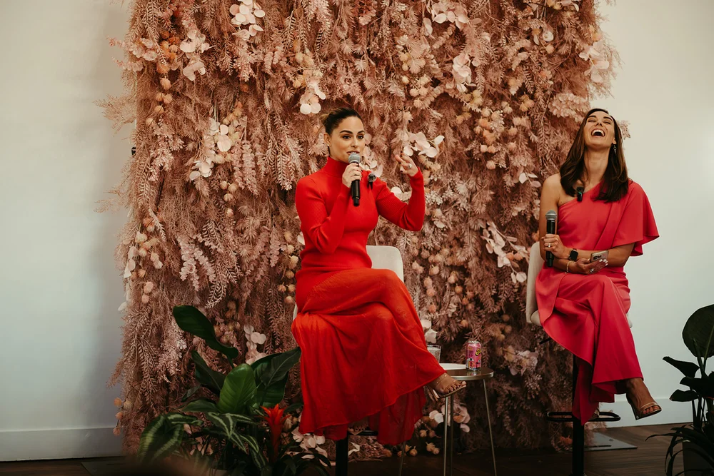 Two women speaking in front of a gorgeous floral backdrop at 14TENN in Nashville