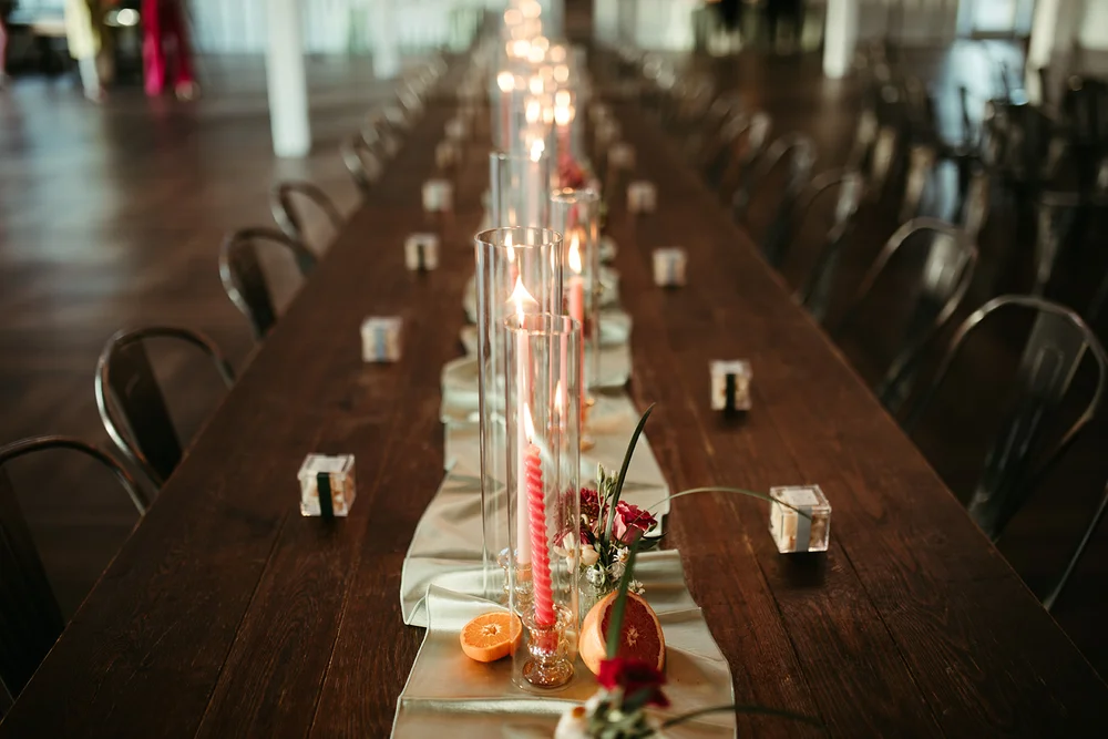 Farm tables set up for a corporate event with candles and flowers at 14TENN in Nashville