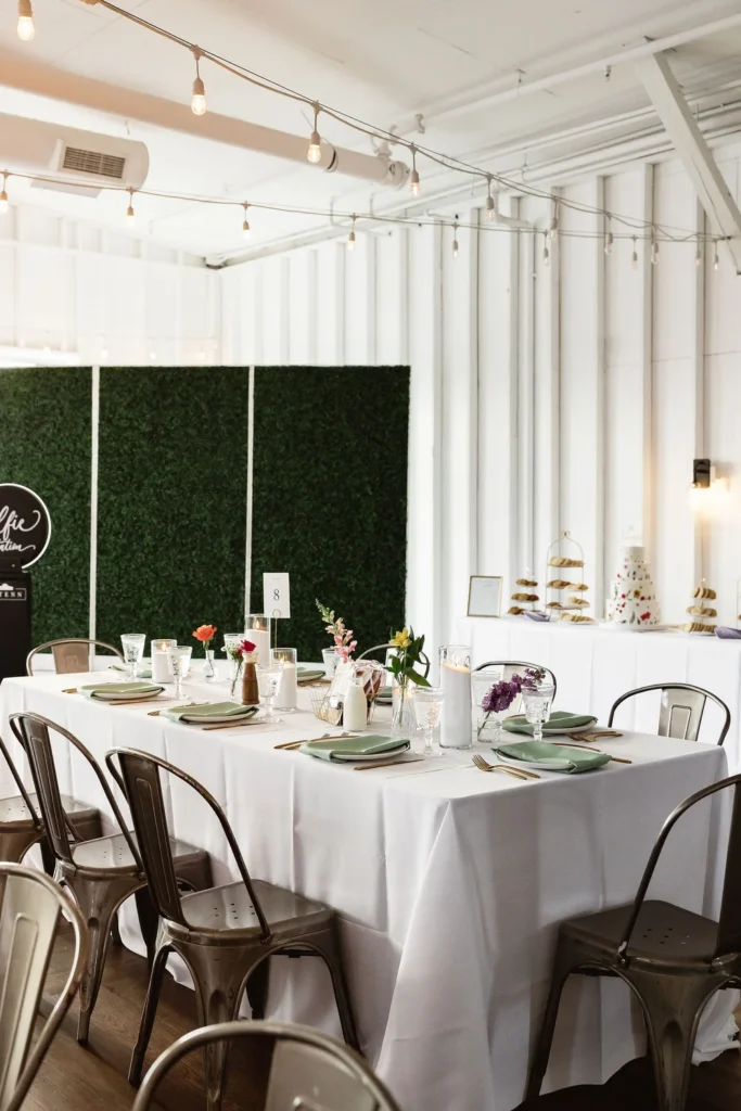 Wedding reception with tables and a hedge wall backdrop for a photo booth set up at 14TENN in Nashville