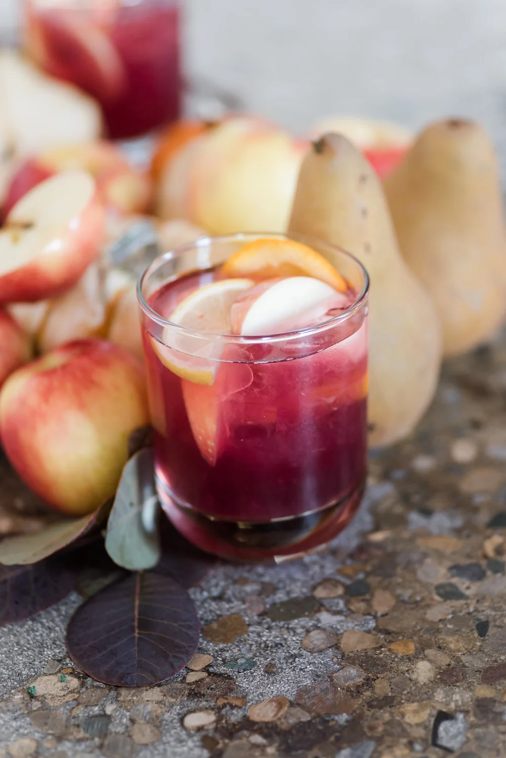 Cocktail with apple and lemon slices surrounded by apples and pears at compant holiday party in Nashville