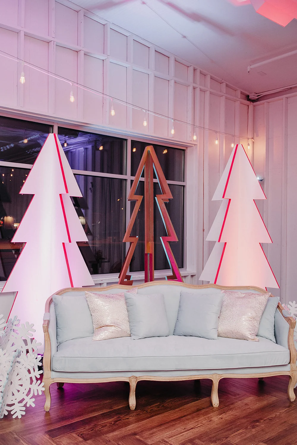 Vintage blue couch with festive Christmas tree cutouts as a holiday backdrop.