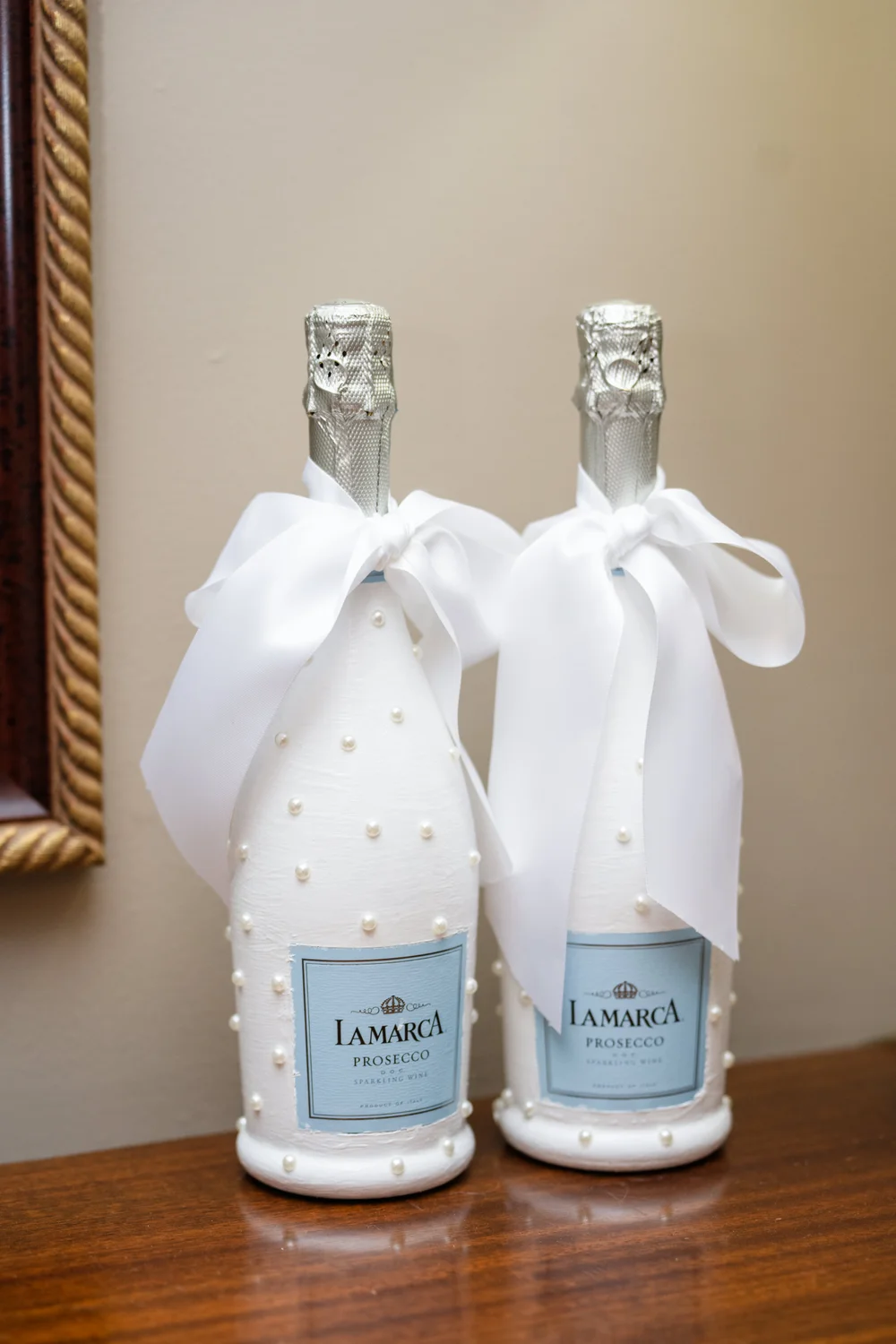 Champagne bottles styled with pearls and white bows for a wedding celebration