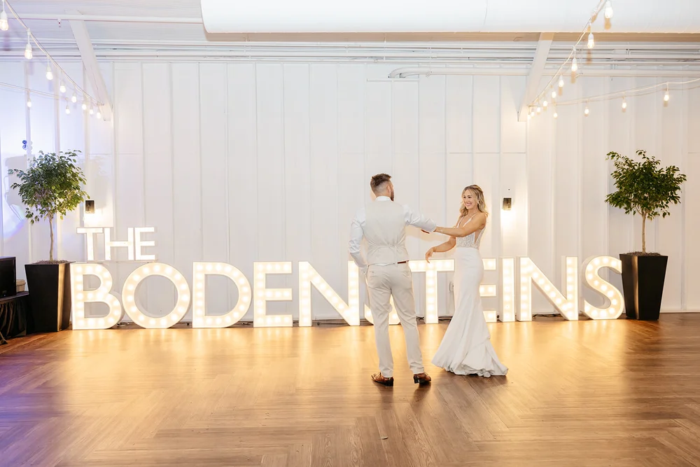 Bride and groom dancing at their wedding at 14TENN in Nashville in front of large light up letters reading the groom's last name