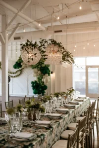 Wedding reception table with overhead chandeliers and greenery